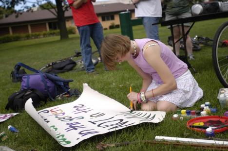 Clara Hoag, freshman in LAS, paints a sign on Saturday at Scott Park in Champaign. A small group of community members united to protest the Republican National Convention in Champaign, since many could not make it to New York to protest. Lauren Lenkowski
