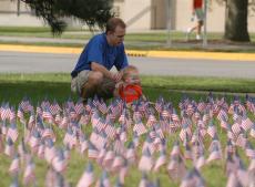 Jeff Brown of Champaign and his 10-month-old son Andy pause to survey 3,030 American flags placed on the front lawn of the College of Law on Saturday. The flags represent the 3,030 people killed on Sept. 11, 2001, and were planted as part of the Never For Claire Napier
