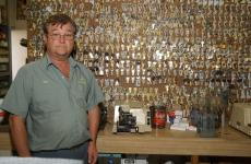 Ron Runyan, owner of Ron´s Campus Locksmith, stands in front of a wall of blank keys at his shop. Runyan recalls that the wall used to be twice as long, but many key lines have been phased out in the last 40 years of business. Online Poster
