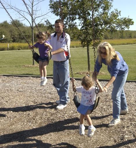 Talon Wright of Urbana swings his 4-year-old daughter, Mariah, while Cindy Groom of Urbana swings Wright´s other daughter, Destiny, 2, Monday afternoon at Meadowbrook Park in Urbana. Swing me higher, Daddy. Swing me higher, Mariah said. Shira Weissman
