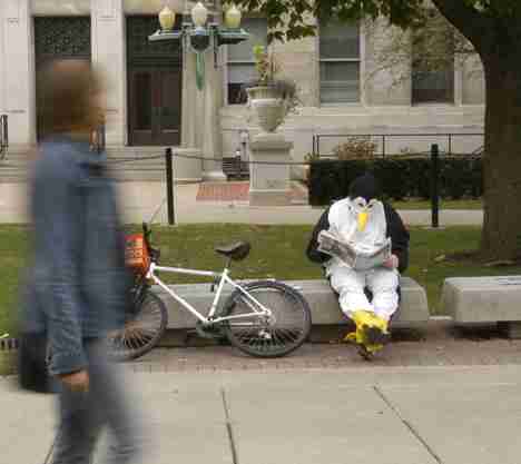 Travis Wayne Hurt (right) reads in front of the Henry Administration Building Thursday. "I felt like wearing (a penguin costume)," Hurt, junior in LAS, said. "It makes people´s days when I go up to someone and give them a high five." Dan McDonald
