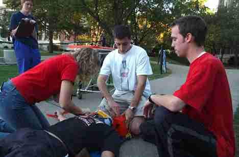 Jen Wilhelm keeps track of Julia Ryself as Jeremy Smiley (center, kneeling) and Nathan Jones run through an emergency medical skills drill on mock patient Chris Johnson outside of Lincoln Hall on Saturday. All students were with the Illini Emergency Medic Online Poster
