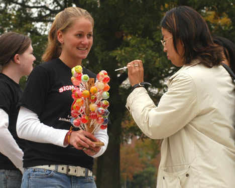 From left: Becky Wingate, freshman in engineering, and Chrissy Alderden, sophomore in LAS, sell a lollipop to graduate student Ejung Choi on the Quad Tuesday afternoon. Wingate and Alderden, members of the Sigma Kappa sorority, are selling lollipops to he Carol Matteucci
