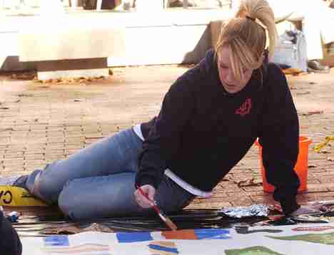 Kira Kohlstedt, member of Student Ambassadors and Student Alumni Association, paints the homecoming mural Monday on the Quad. Registered Student Organizations all took part in painting the mural as a way to bring the RSOs together according to Maggie Evan Carol Matteucci
