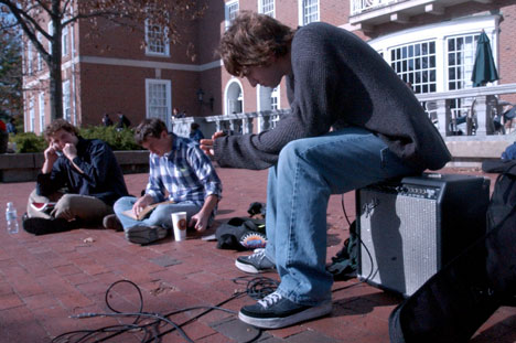 His guitar beside him, Peter Manhart, Champaign resident, waits with Chase McCoy, junior in ACES and Tazio Kubbs, senior in ACES, outside of the Union on Tuesday until classes ended. Manhart, who had been playing his guitar previously to publicize his ban Online Poster
