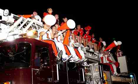 The Illini Cheerleaders ride a fire truck at the Homecoming Parade on Friday night. The parade featured the interim chancellor, members of the Homecoming Court and various floats from different organizations on campus. Lauren Lenkowski
