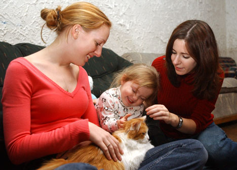 Megan Bukowski, left, junior in applied life sciences, and Lauren Suspenzi, far right, sophomore in applied life studies, pet Malenka the cat with Sadie, 2, Wednesday evening at the Tau Epsilon Phi Fraternity. Fraternity members and their friends had a ho Online Poster
