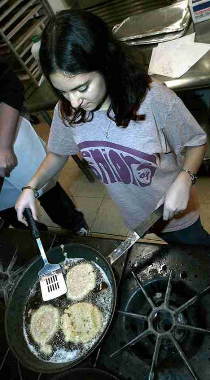 Sheila Das, freshman in ACES, cooks potato latkes at Hillel on Tuesday night as part of the first night of Hanukkah. Since Hanukkah falls during the semester this year, some students celebrate at Hillel, which offers candle-lighting, dreidel contests and Online Poster
