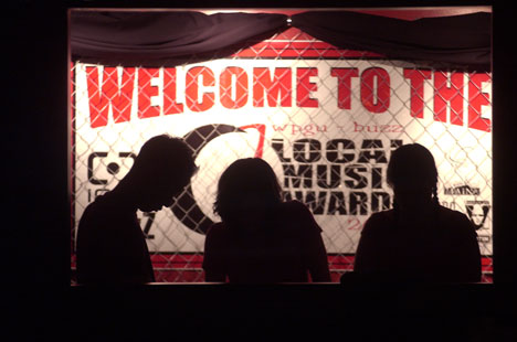 From left to right in silhouette, Peter Jang, senior in LAS, Becky Kaiser, freshman in LAS, and Aileen Connolly, junior in communications, help to prepare paper bag lamps at the Highdive in Champaign on Wednesday night. The lamps will line the streetside Online Poster
