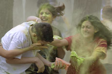 Lavina Chaturvedi, rear left, and Divya Chandiramanic, both freshmen in LAS, strike Harsh Mehta, freshman in LAS, with colored flour during a celebration of Holi in the Ilini Grove on Sunday. Members of the Hindu Student Council had been mixing tempera pa Online Poster

