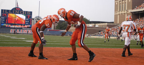 Junior fullback Jason Davis congratulates sophomore tight end Melvin Bryant on his touchdown reception as Rattlesnake Craig Swain walks away Sept. 4, 2004, at Memorial Stadium. Illinois head coach Ron Zook has yet to schedule an extra game and is still un Daily Illini file photo
