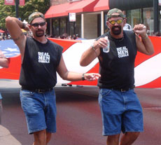 Two men with T-shirts reading Real Men Cuddle help carry a giant U.S. flag during Chicago´s 36th Annual Gay and Lesbian Pride Parade last Sunday. An estimated 400,000 attended the parade, which began on Halsted Street at Belmont Avenue. Ed Thomson
