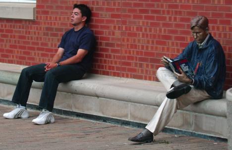 Edgar Mata (left), senior in Engineering, takes a break from his work Thursday evening next to a statue outside of Grainger Engineering Library. Nick Kohout
