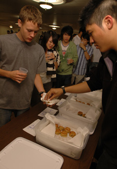 Brian Lin, sophomore in engineering, serves a moon cake to Ted Sanders, sophomore in LAS, at the Annual Chinese Mid-Autumn Festival Friday night at the Union. Austin Happel
