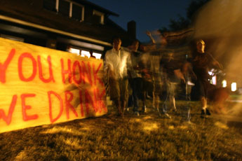 Students leave a house party on First St. in Champaign on Saturday night. They walk by a sign that says, You honk, we drink. Josh Birnbaum
