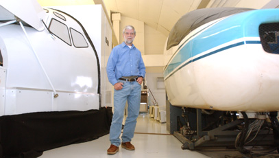 Professor Christopher Wickens stands between a 737 Boeing Simulator and a General Aviation Trainer 3 Simulator at Willard Airport on Thursday. Ben Cleary
