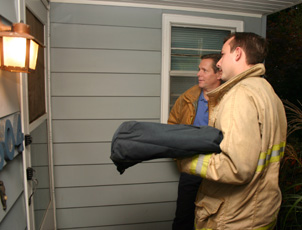 Dave Wisher (left) and Mike Ashby, both Urbana firefighters, deliver pizza to an Urbana home Wednesday as part of the Change your Clocks, Change your Batteries smoke detector campaign. Regina Martinez
