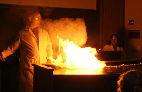 Professors Jesse Miller (left) and Lauren Denofrio (right), both of Urbana, set fire to a cloth string made of smokeless gunpowder in the Christmas Chemistry Demo in Noyes Laboratory on Friday night. The audience for the demo ranged from college students AJ Kane
