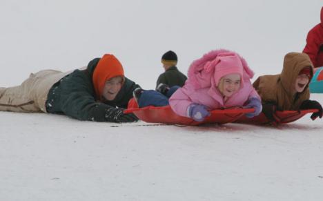 Jack Jarboe gives the starting push to six-year-old twins, Joel and Jenny Jarboe, as they sled down Hackberry Hill on Sunday. The Jarboes spent four hours on Saturday sledding and returned early Sunday afternoon. Adam Babcock
