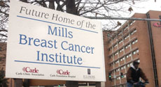 A sign marks the spot on Tuesday afternoon where the Mills Breast Cancer Institute will be built. The parking lot across from Carle Hospital, on the corner of University and Orchard will be cleared for the site. Adam Nekola
