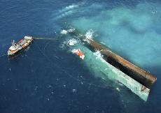 With the help of air lift bags, air injection in ballast tanks and pull from two tugboats, the Spiegel Grove, a 510-foot retired Navy ship, begins to rotate in this June 10, 2002, file photo in the Florida Keys National Marine Sanctuary before it is prema The Associated Press
