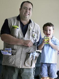 Marcus Melnick, with his son, Ari, in their Buffalo Grove, Ill., home, wears the Daddy Diaper vest that he invented as an alternative to the diaper bag. The Associated Press
