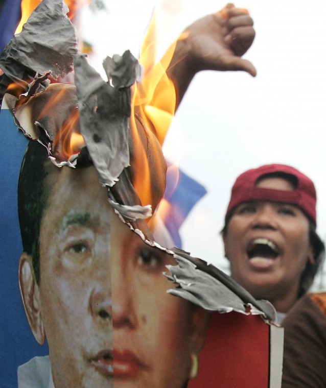 A woman activist shouts slogans as they burn a double-faced poster of Philippine President Gloria Macapagal Arroyo and toppled strongman Ferdinand Marcos during a rally to mark the 34th anniversary of martial law declared by Marcos in suburban Manila Thur AP Photo/Aaron Favila
