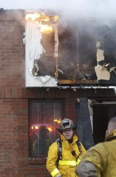 An unidentified firefighter looks on as the State of Illinois Department for Children and Family Services, 1806 Woodfield Dr., in Savoy, burns from within. The roof fire was reported by a motorist passing by who notified the occupants in time to safely e Beck Diefenbach
