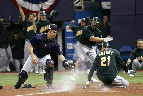 Oakland Athletics' Mark Kotsay (21) scores with a inside-the-park two-run home run off Minnesota Twins pitcher Dennys Reyes as Minnesota Twins catcher Joe Mauer, left, gets the late throw from centerfield during the seventh inning of an American League Division Series baseball game in Minneapolis, Wednesday, Oct. 4, 2006. (AP Photo/Ann Heisenfelt)
