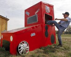 Oliver Schaefer demonstrates the only way to enter the NASCAR outhouse, which includes a television inside, Oct. 10 The Associated Press
