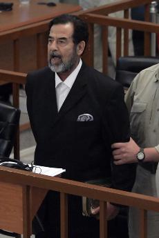 Former Iraqi leader Saddam Hussein yells at the court as he receives his verdict as a bailiff attempts to restrain him during his trial held under tight security in the heavily fortified Green Zone, in Baghdad, Iraq, Sunday. The Associated Press
