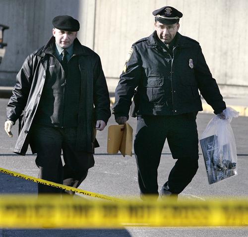 Two members of the Massachusetts Bay Transit Authority police carry a bag of circuit board pieces after a suspicious package containing the boards was detonated by the Boston Bomb Squad near the Sullivan Square subway station in Boston, Wednesday morning, (AP Photo/Adam Hunger)
