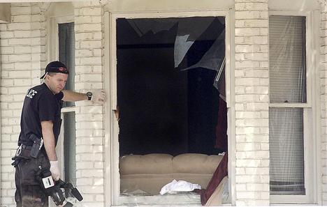Danville police officer Chad Turner looks for evidence near a window through which a 30-year-old man is believed to have jumped before he collapsed and died in the middle of Main Street in Danville, Ill., Sunday. The bodies of two women were found inside Holly Hart, AP
