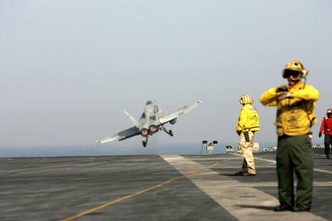 A flight-deck director signals moments after an F/A 18 C plane leaves the flight deck aboard the USS John C. Stenniis Tuesday. Kamran Jebreili, AP
