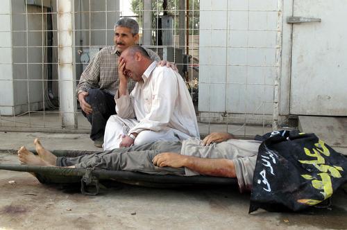 Relatives grieve next to a body of a victim of violence in Baqouba, in Diyala province, Iraq, Wednesday. Since troops launched the security crackdown in Baghdad, Sunni militants are believed to have found haven in nearby areas. Adem Hadei, AP
