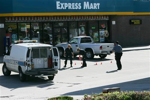 Police outline bullet casings and place small cones near the evidence as they investigate a crime scene at the Valero Express Mart in Kansas City, Mo., Sunday, April 29, 2007, where a police officer was shot in the arm after pulling over a person driving The Associated Press
