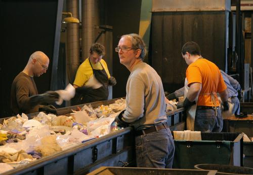 From left, Jamie Thompson of Savoy, Alaric Schaufele, Urbana, Alan Knight, Champaign, and Ben Evans, Urbana, sort through solid waste at the Waste Transfer Station in Champaign on Tuesday. Paper, cardboard, plastic and aluminum are separated out of the tr Beck Diefenbach
