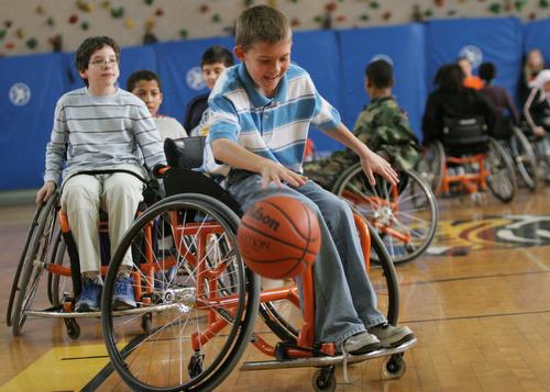 Jefferson Middle School student Cayden Bergschneider tries to dribble the ball while in a wheelchair on Thursday at the school during a wheelchair basketball exhibition. The Illinois wheelchair basketball teams put on the exhibitions to educate and inform Beck Diefenbach
