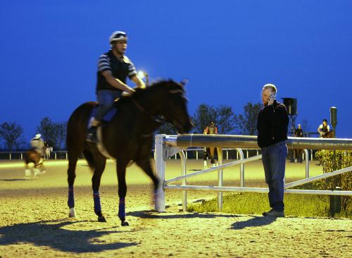 Trainer Todd Pletcher talks on the phone as he stands trackside before dawn at Keeneland in Lexington, Ky. on Tuesday. The Kentucky Derby is Saturday. Ed Reinke, AP
