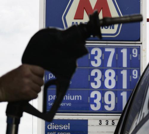 A gas pump nozzle is silhouetted against a gas price sign showing prices over $3.70 at a station near downtown Chicago Tuesday, May 15, 2007, as prices continued to soar. Most Americans are locked in to their driving habits, and can do little to alter the The Associated Press
