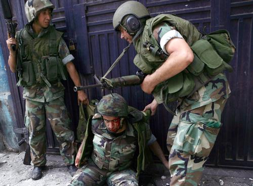 A wounded Lebanese soldier on the ground receives help from his colleagues after he was injured in clashes with fighters from an Islam militant group, in the north city of Tripoli, Sunday. Lebanese security forces fought Islamic militants in the northern The Associated Press
