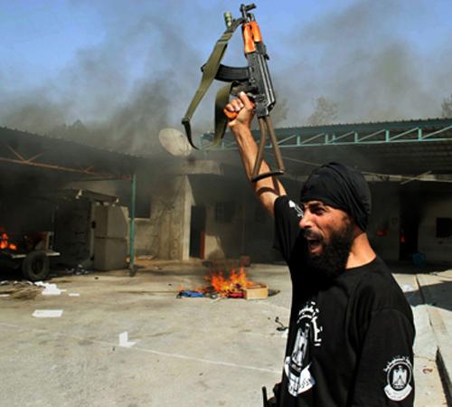 A Hamas militant celebrates next to a burning building at the headquarters of the Palestinian security forces loyal to President Mahmoud Abbas after capturing it in fighting in Rafah, southern Gaza Strip Thursday, June 14, 2007. Hamas overran two of the r The Associated Press
