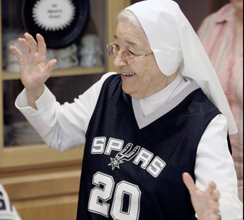 Sister Rosalba Garcia, wearing a San Antonio Spurs jersey, center, Sister Angelina Gomez, holding a Spurs flag, and several other nuns of the Salesian Sister of Mary Immaculate Province gather for a photo in front of their San Antonio Spurs banner in San The Associated Press
