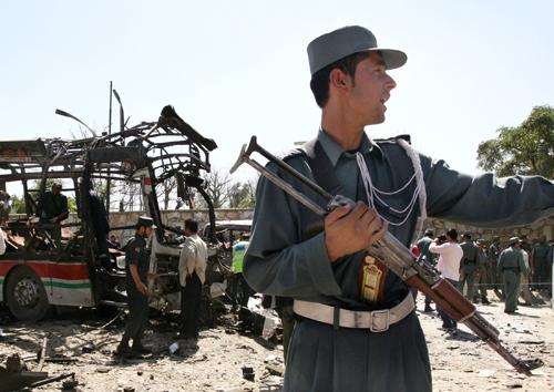 An Afghan police officer gestures at the scene of a bomb blast in Kabul, Afghanistan on Sunday. The bomb ripped through a police bus, left, in a bustling area of Kabul on Sunday, killing at least 35. Musadeq Sadeq, The Associated Press
