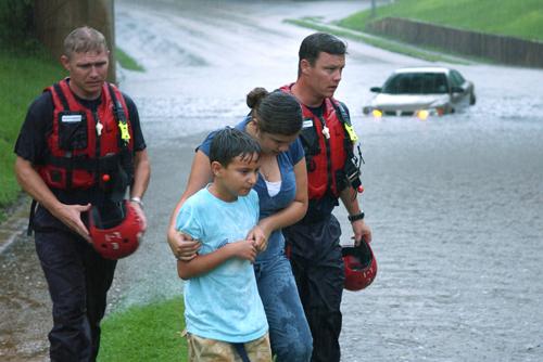 Tyler firefighters Jason Beasley, left, and Joey Hooton, right, rescue an unidentified woman and a child after their car became stranded in flood waters under a bridge in Tyler, Texas, Tuesday July 3, 2007. The Associated Press
