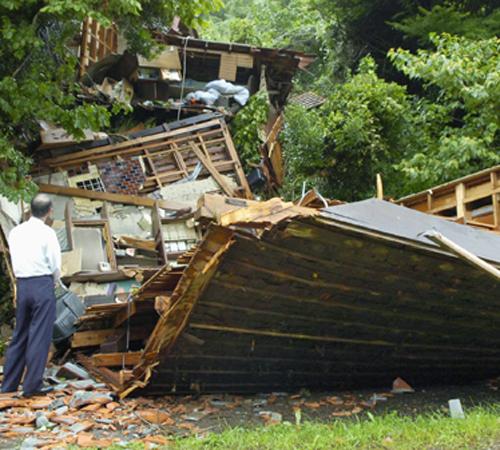 A man looks at a collapsed house which was caused by landslide due to a typhoon in Isumi city, Chiba prefecture, east of Tokyo, Sunday, July 15, 2007. A typhoon expected to hit Tokyo missed the capital and moved toward northeastern Japan on Sunday after l Kyodo News
