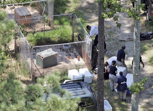 Officials carry out evidence as they search the grounds behind a home owned by Michael Vick in Smithfield, Va., on July 6. A grand jury indicted Vick on Tuesday for his involvement in dogfighting. Steve Helber, The Associated Press
