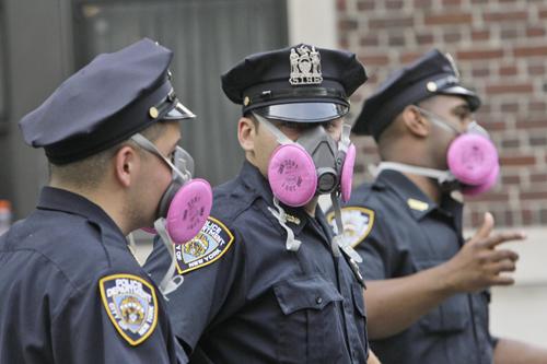 New York city police officers wear masks while blocking pedestrians from entering Park Ave. above 40th St., Thursday, July 19, 2007 in New York. A massive geyser of steam and debris that erupted through a midtown Manhattan street left asbestos in the dust Mary Altaffer, The Associated Press
