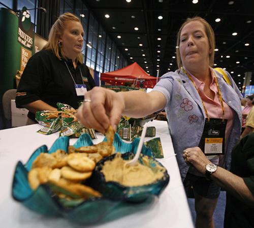 Robin Lightfoot, left, of Garden City, Kan., listens to Kathy Cheop as she samples hummus at the Wild Garden booth at the School Nutrition Association annual meeting in Chicago on Tuesday, July 17, 2007. The push for healthy options has food companies scu Brian Kersey, The Associated Press

