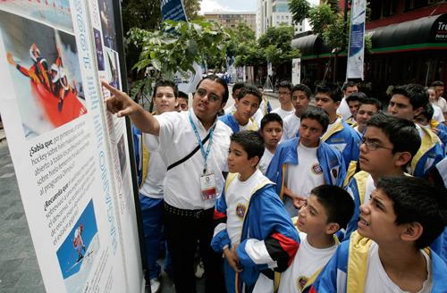 Volunteer Fernando Kevin explain the history of the Olympic games to school children using banners along a street of Guatemala City, Thursday, July 5, 2007, as part of the extra activities of the 119th Session of the International Olympic Committee. The Associated Press
